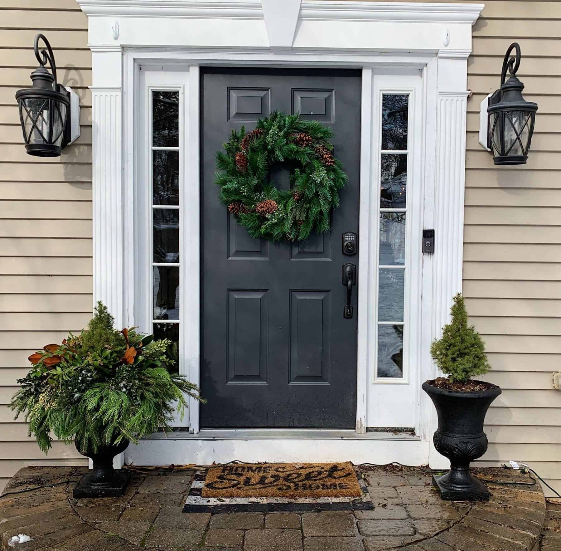 how the front porch looks with a single outdoor planter with alberata spruce and another planted with fresh christmas greenery from the garden