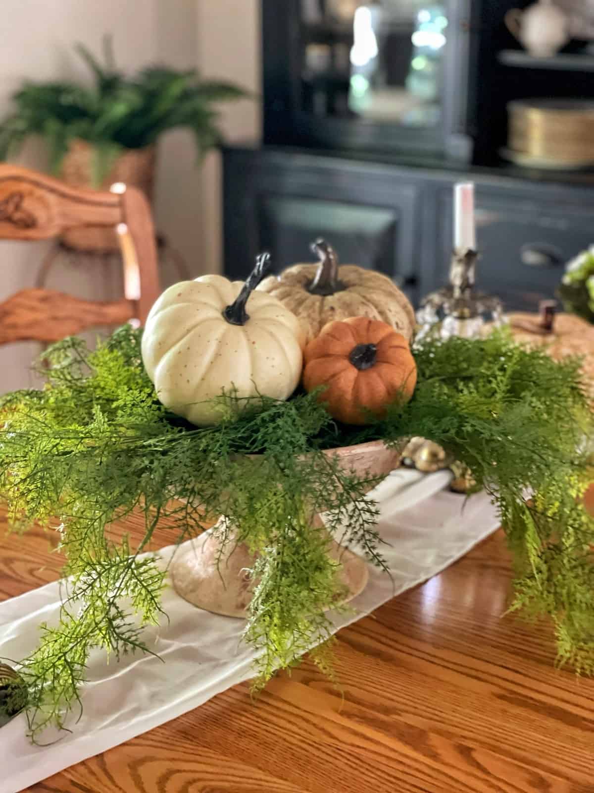 ceramic bowl that was upcycled to look like stone filled with festive pumpkins and fall decor in a dining room on an wood table. Easy DIY decor you can make in less than a day.