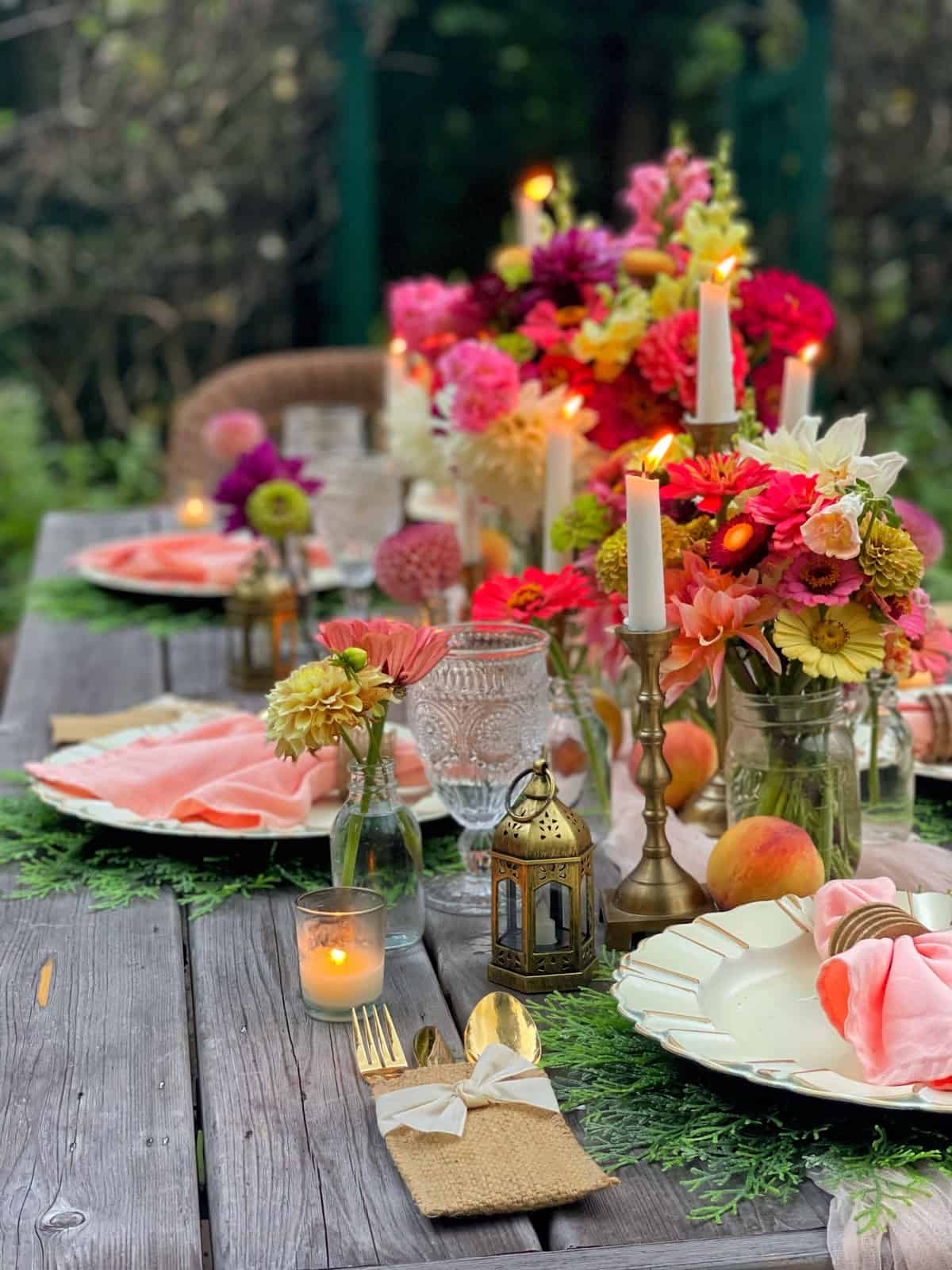 fresh cut flowers from the cutting garden with zinnias, dahlias, snapdragons in vases and mason jars with peaches, taper candles, votives and small gold lanterns with peach table decor