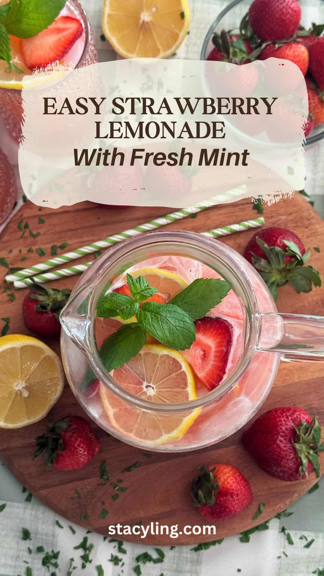 A glass pitcher of strawberry lemonade with lemon slices and mint leaves sits on a wooden board, surrounded by fresh strawberries, lemon halves, and two green striped straws. Text reads: "Easy Strawberry Lemonade Recipe With Fresh Mint.