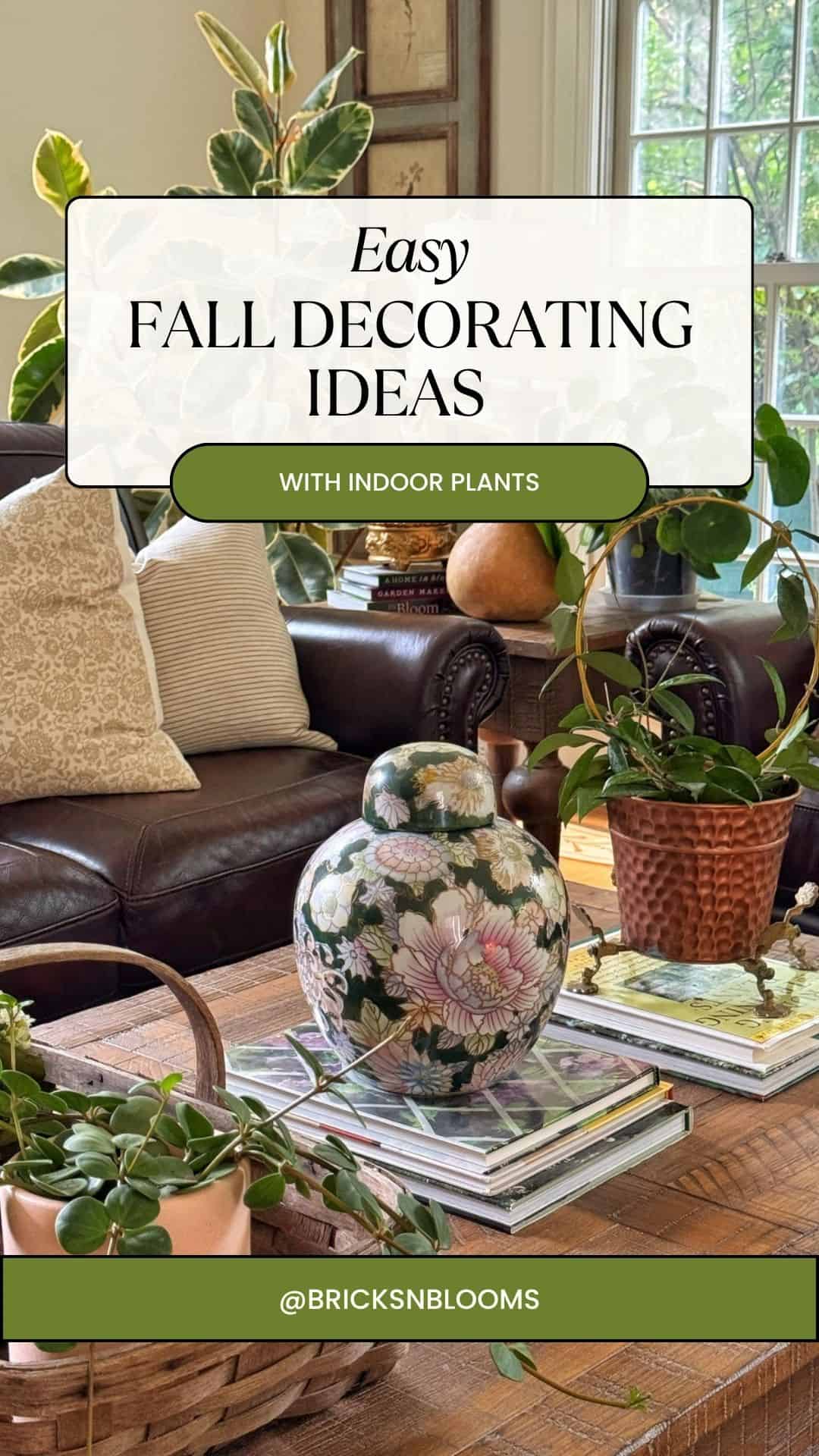 A living room with a leather sofa, patterned pillows, various indoor plants in pots, a floral vase on a stack of books, and large windows letting in natural light offers endless indoor plant decor ideas. Text overlay: Easy Fall Decorating Ideas with Indoor Plants.